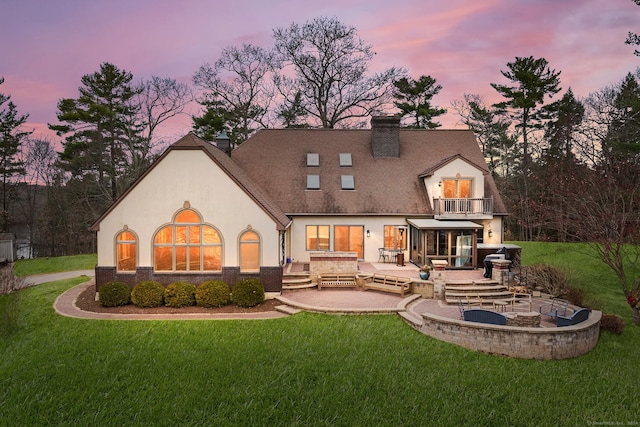 back house at dusk featuring a yard, a patio area, outdoor lounge area, and a balcony