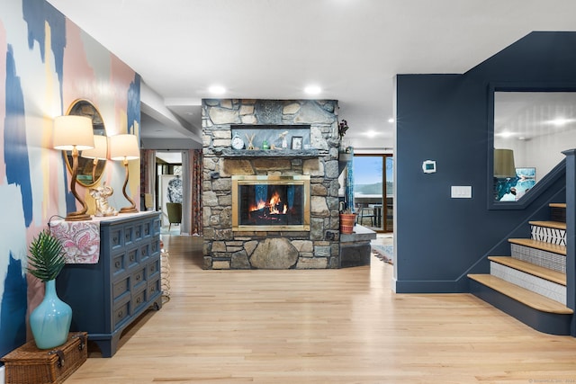 living room featuring a stone fireplace and light wood-type flooring