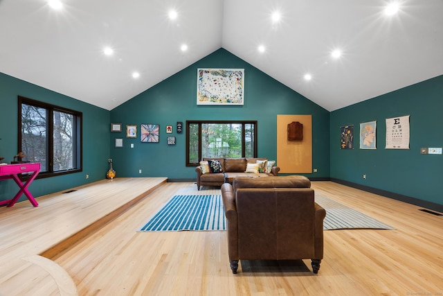 living room with high vaulted ceiling, basketball court, and light hardwood / wood-style flooring