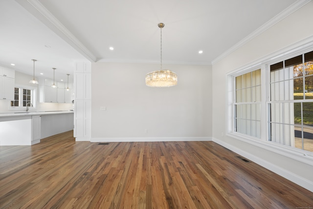 unfurnished dining area featuring dark hardwood / wood-style flooring, crown molding, a notable chandelier, and sink