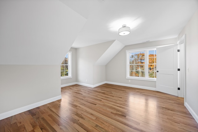 bonus room with lofted ceiling and light wood-type flooring