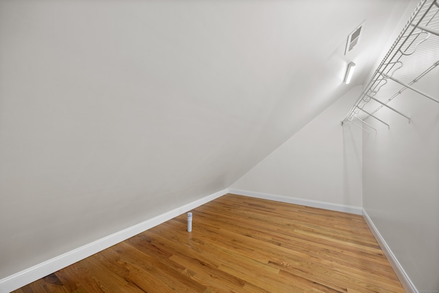 walk in closet featuring hardwood / wood-style flooring and vaulted ceiling