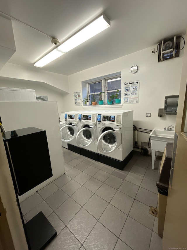 clothes washing area featuring washing machine and dryer, sink, and light tile patterned flooring