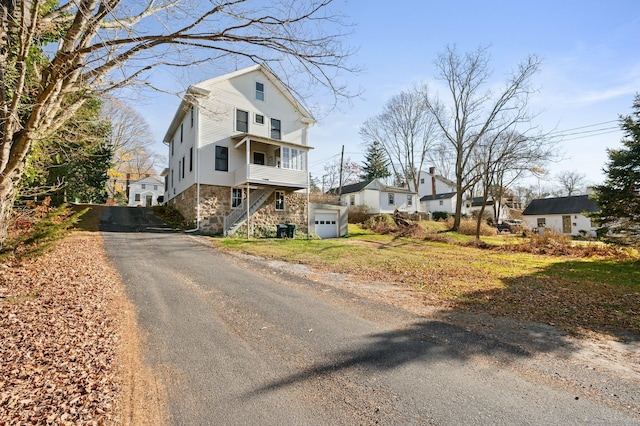 46 Lyme St, Old Lyme, CT 06371 - view of front of house with asphalt driveway, stone siding, a garage, a residential view, and stairs