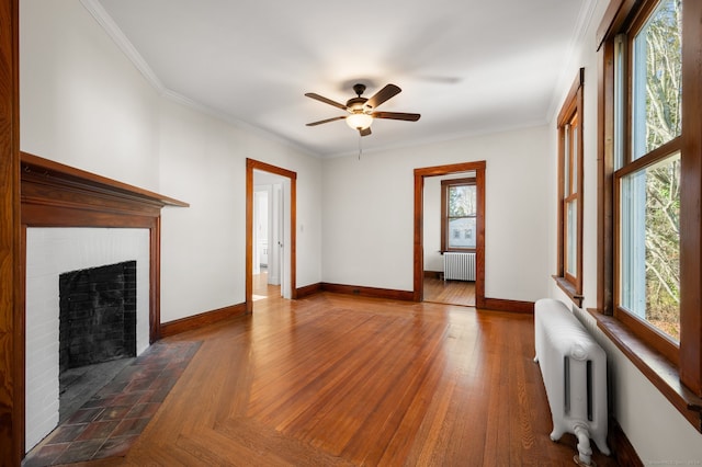 unfurnished living room featuring dark hardwood / wood-style floors, a brick fireplace, radiator, and crown molding