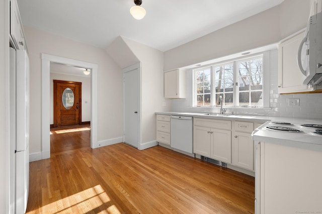 46 Lyme St, Old Lyme, CT 06371 - kitchen with white appliances, tasteful backsplash, light wood finished floors, white cabinets, and light countertops