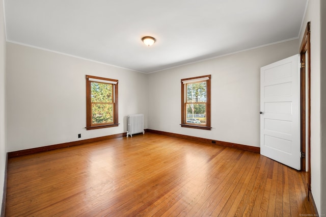 empty room featuring radiator heating unit, crown molding, and wood-type flooring