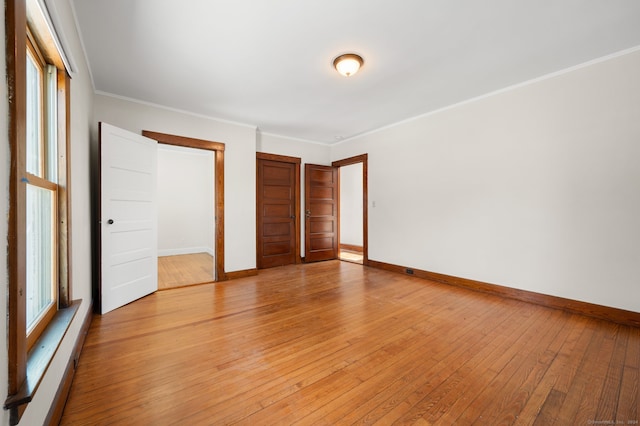 unfurnished bedroom featuring a closet, ornamental molding, and light hardwood / wood-style flooring