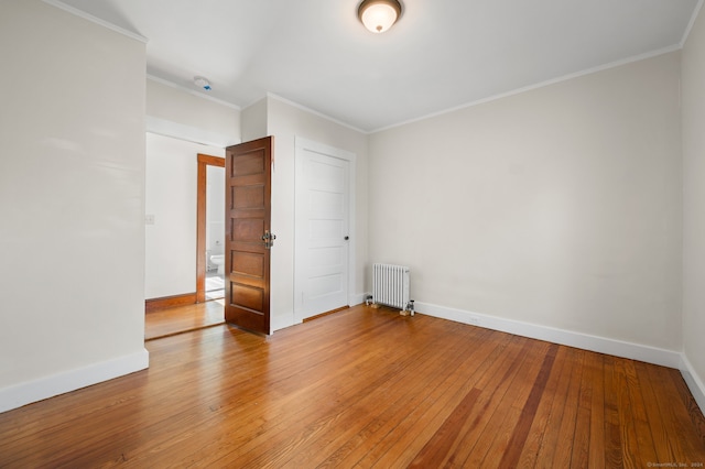 spare room with radiator, ornamental molding, and hardwood / wood-style flooring