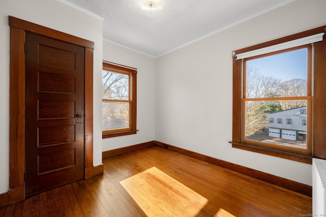 empty room with radiator, ornamental molding, a textured ceiling, and hardwood / wood-style flooring