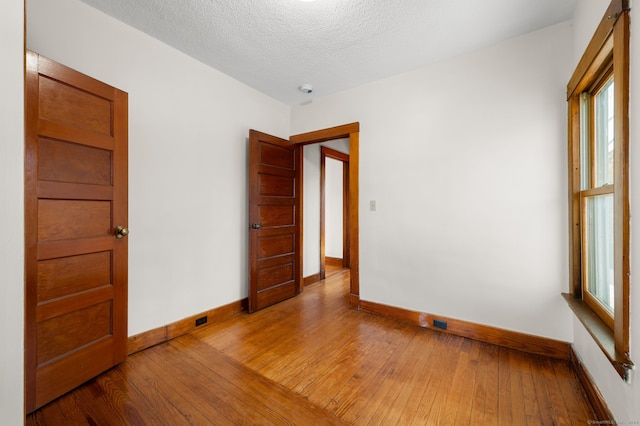 unfurnished room featuring hardwood / wood-style flooring and a textured ceiling