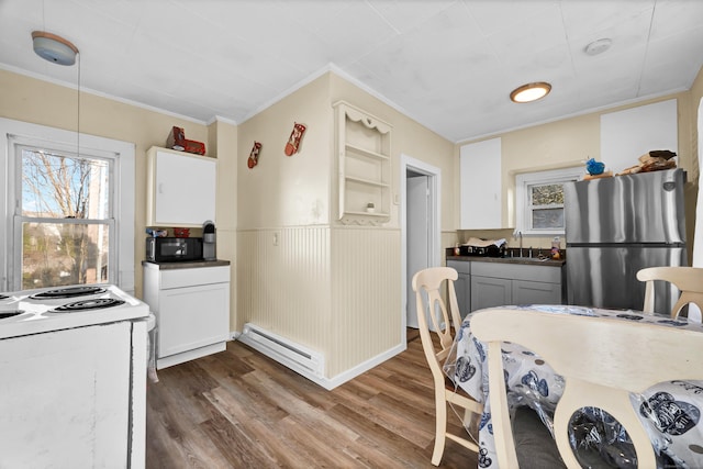 kitchen with a healthy amount of sunlight, stainless steel fridge, a baseboard radiator, and decorative light fixtures