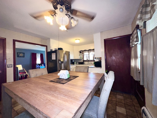 dining space with ceiling fan, a baseboard heating unit, and sink