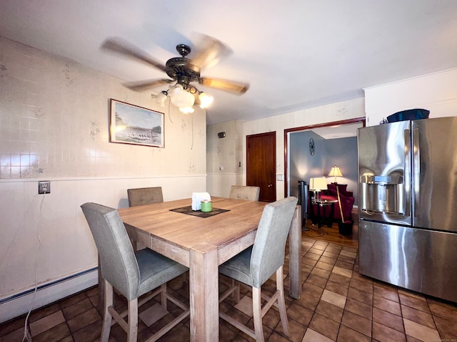 dining area with baseboard heating, ceiling fan, and tile walls