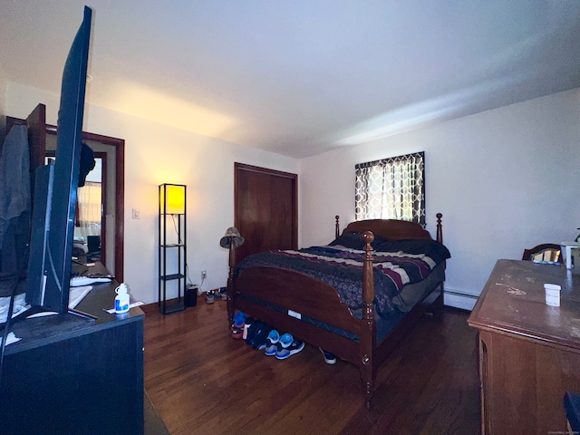 bedroom with dark hardwood / wood-style flooring, multiple windows, and a baseboard heating unit