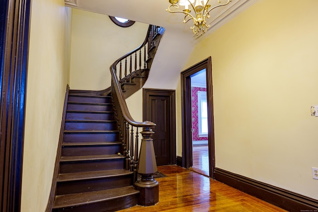 stairway featuring hardwood / wood-style flooring, a notable chandelier, and crown molding