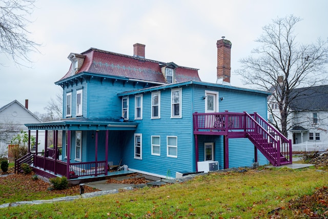 rear view of property featuring ac unit, a porch, and a yard