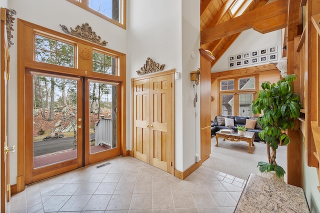 doorway to outside with beam ceiling, light tile patterned floors, high vaulted ceiling, and french doors