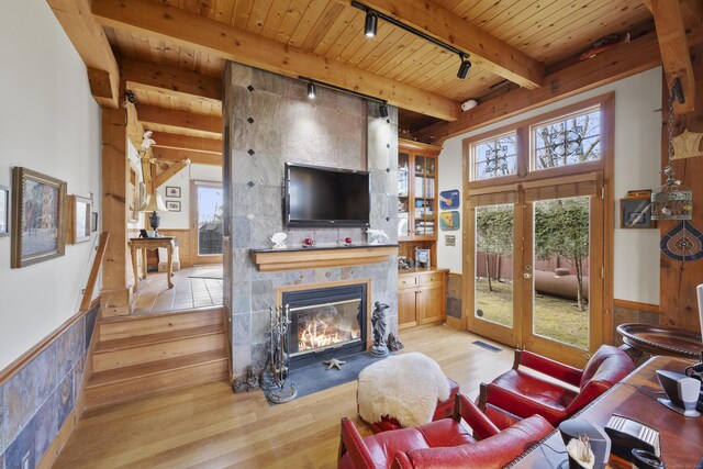 living room with french doors, a large fireplace, track lighting, and light hardwood / wood-style floors