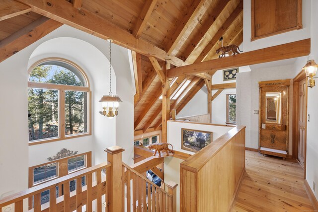 hall featuring beam ceiling, light wood-type flooring, wooden ceiling, and an inviting chandelier