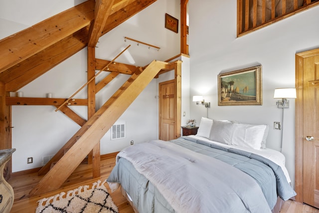 bedroom featuring high vaulted ceiling and light hardwood / wood-style flooring