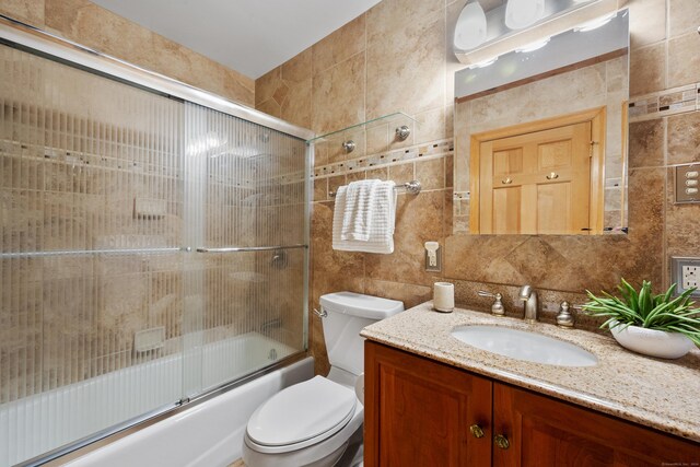 full bathroom with backsplash, vanity, tile walls, enclosed tub / shower combo, and toilet