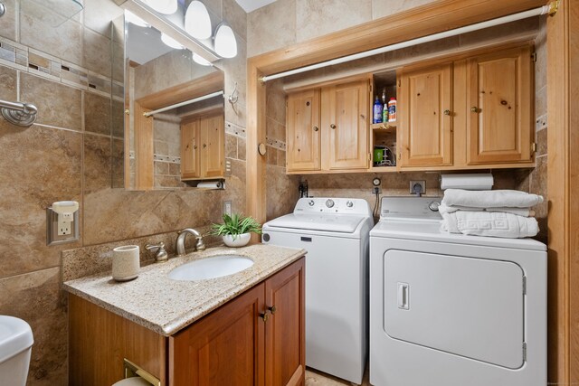 laundry area with separate washer and dryer, tile walls, and sink