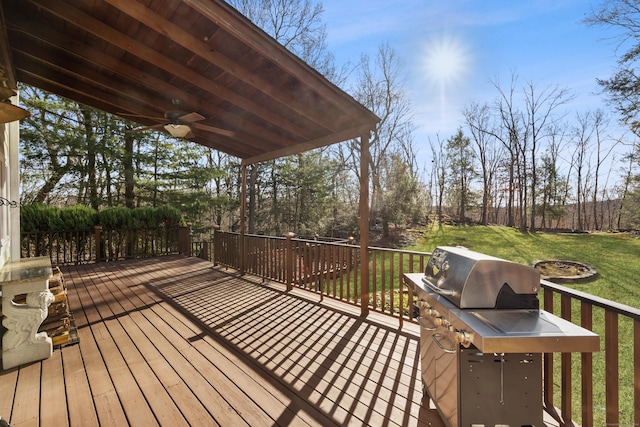 wooden terrace featuring grilling area, ceiling fan, and a lawn