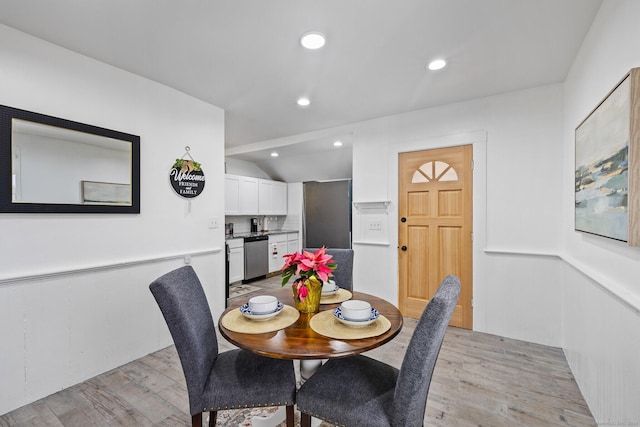 dining space with light hardwood / wood-style floors and vaulted ceiling