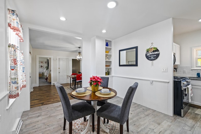 dining room with baseboard heating, light hardwood / wood-style flooring, and built in features