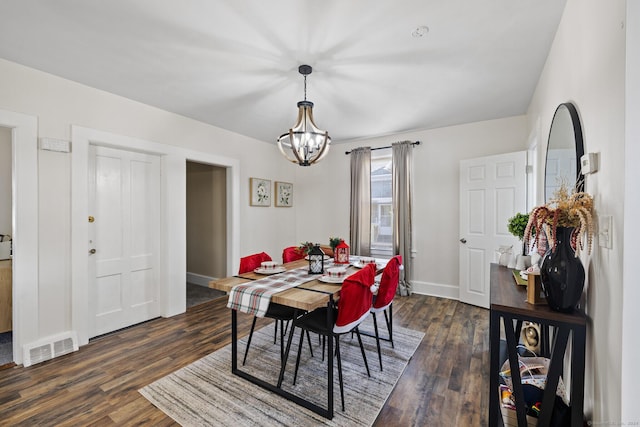 dining space featuring dark hardwood / wood-style flooring and a notable chandelier