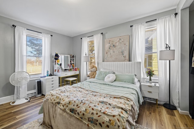 bedroom with multiple windows and hardwood / wood-style flooring