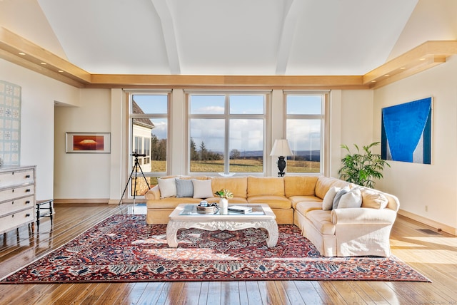 living room featuring beam ceiling, hardwood / wood-style flooring, and high vaulted ceiling