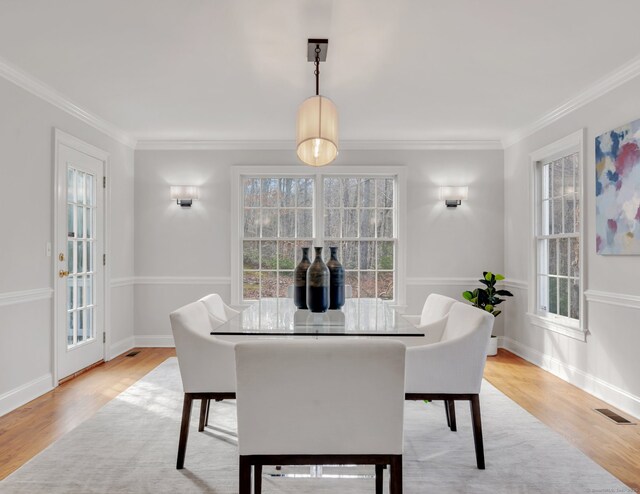 dining area featuring light wood-type flooring, plenty of natural light, and crown molding