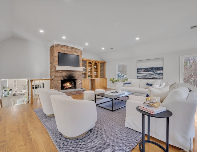 living room featuring a fireplace, light hardwood / wood-style floors, and vaulted ceiling