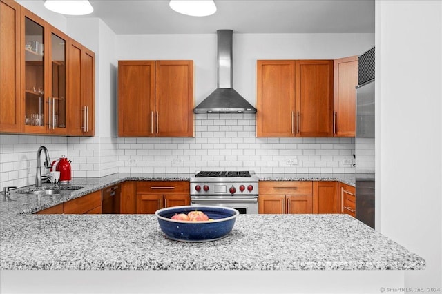 kitchen with decorative backsplash, light stone counters, high end stainless steel range, and wall chimney exhaust hood