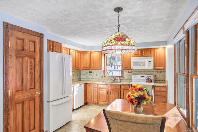 kitchen featuring pendant lighting, white appliances, sink, light stone countertops, and tasteful backsplash