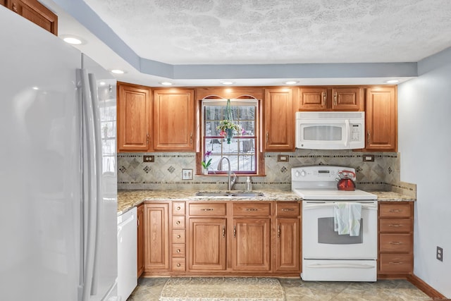 kitchen with light stone countertops, backsplash, a textured ceiling, white appliances, and sink