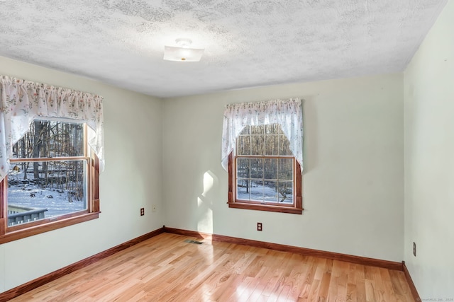 unfurnished room with hardwood / wood-style floors and a textured ceiling