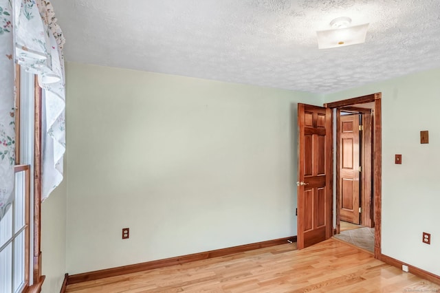 unfurnished room with a textured ceiling and light wood-type flooring