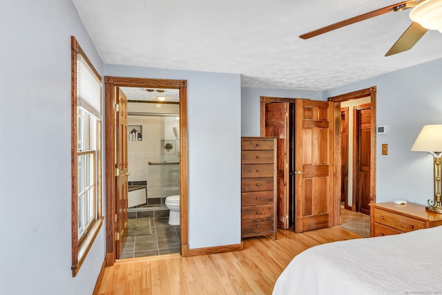 bedroom featuring light wood-type flooring, ensuite bathroom, and ceiling fan