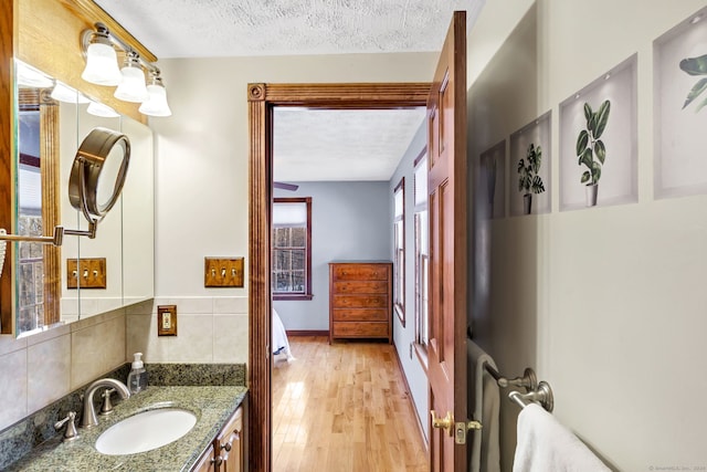 bathroom with vanity, a textured ceiling, tasteful backsplash, and hardwood / wood-style flooring