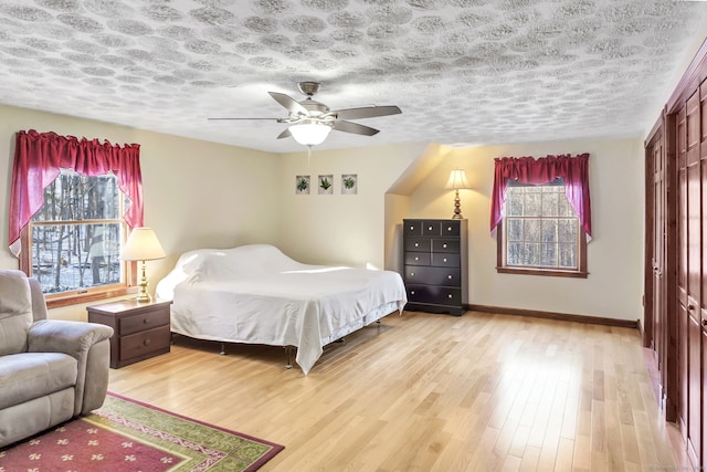 bedroom featuring a textured ceiling, light wood-type flooring, a closet, and ceiling fan