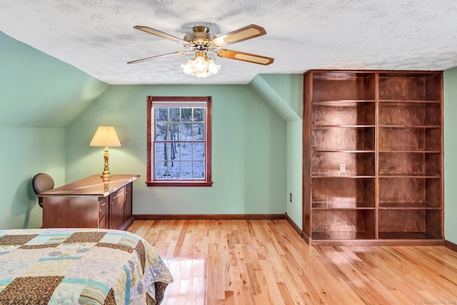 bedroom featuring a textured ceiling, ceiling fan, light hardwood / wood-style flooring, and vaulted ceiling