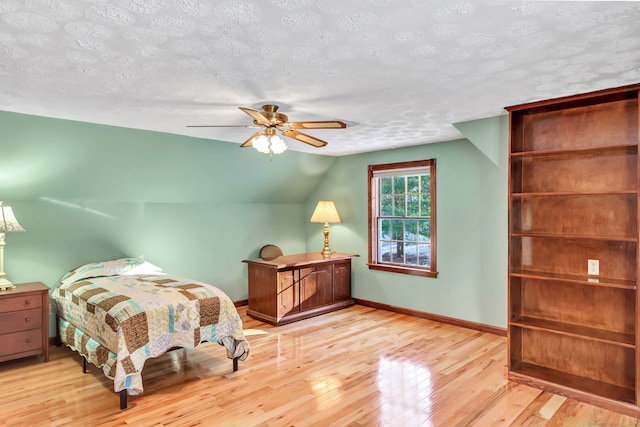 bedroom featuring a textured ceiling, light hardwood / wood-style floors, ceiling fan, and lofted ceiling