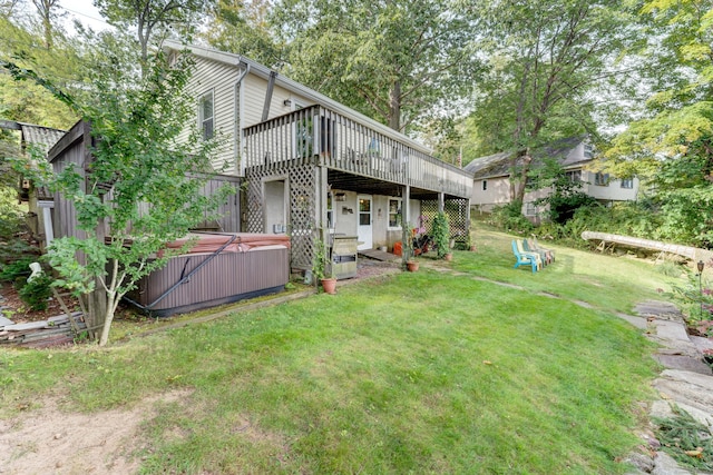 rear view of property featuring a lawn, a hot tub, and a deck