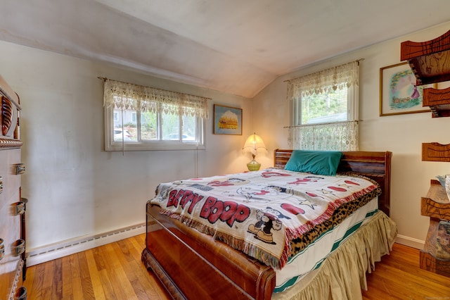 bedroom with light wood-type flooring, vaulted ceiling, and a baseboard heating unit