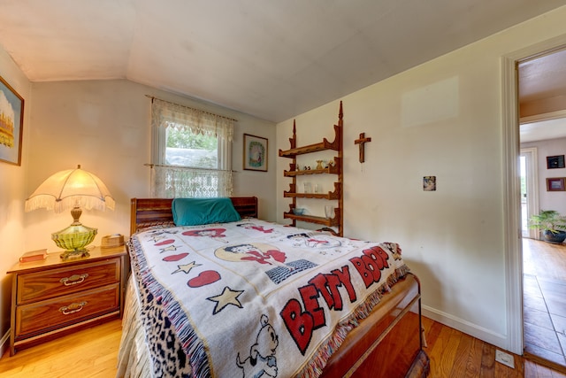 bedroom featuring lofted ceiling and light hardwood / wood-style flooring