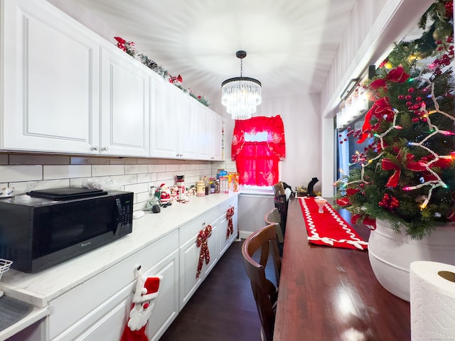 kitchen with an inviting chandelier, dark hardwood / wood-style flooring, white cabinetry, and tasteful backsplash