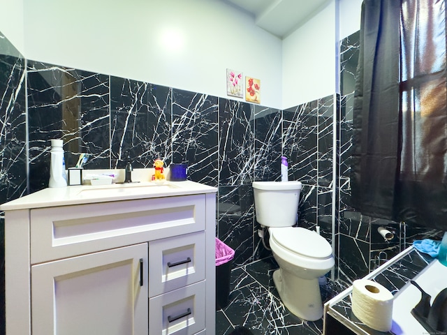 bathroom with vanity, tile walls, and toilet